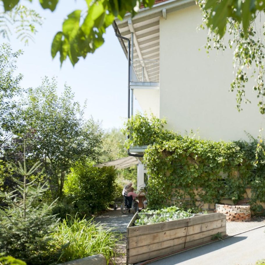 Begrünter Außenbereich des Schulhauser Hofs in Iggensbach mit gepflegter Gartenanlage und einladenden Aufenthaltsmöglichkeiten im Freien.
